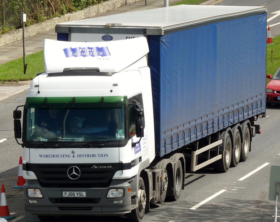 Ein großer Logistik-LKW auf der Autobahn, der die physische Lieferung von Waren an Restaurants darstellt.